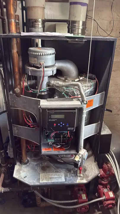 Gas-fired boiler with the front cover open, showing the controller, blower and red circulator pumps