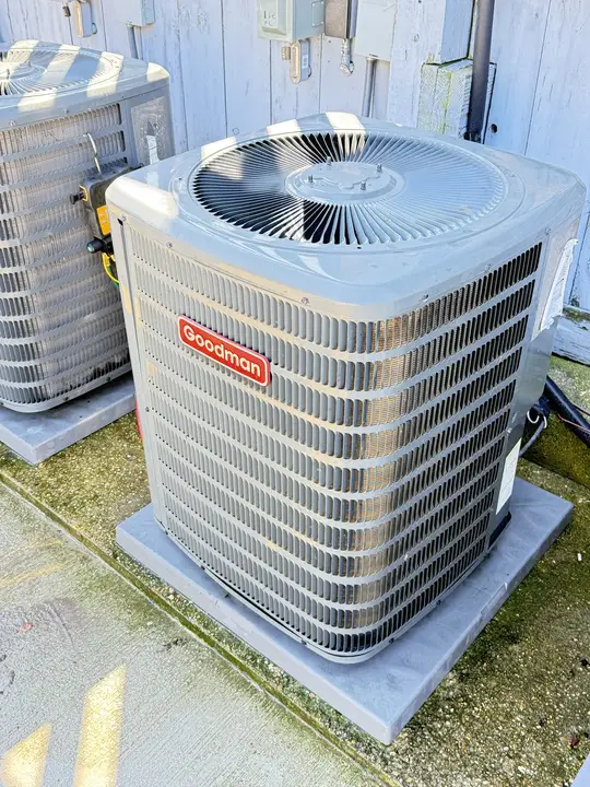 Goodman air conditioner condenser on a pad with a gauge set connected for testing