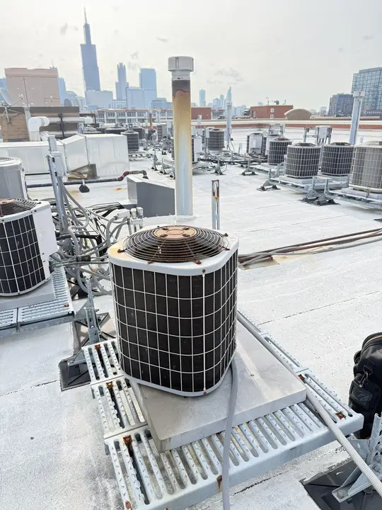 Rooftop condensers on a Chicago apartment building with the Willis Tower in the distance